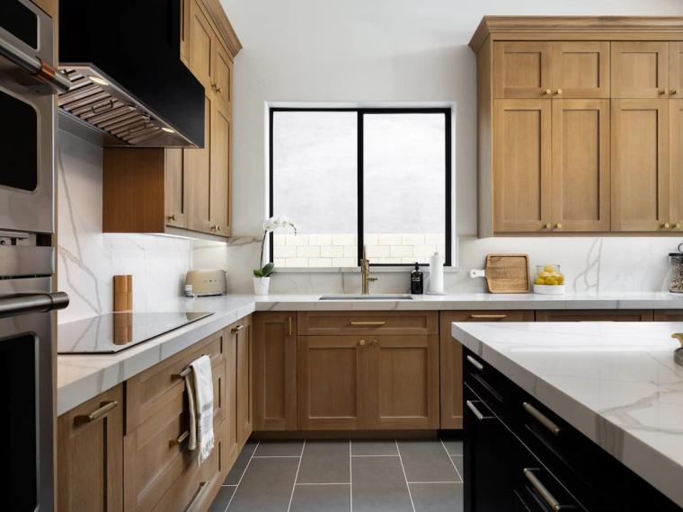 Kitchen with oak cabinets, veined marble counters and stainless double wall ovens