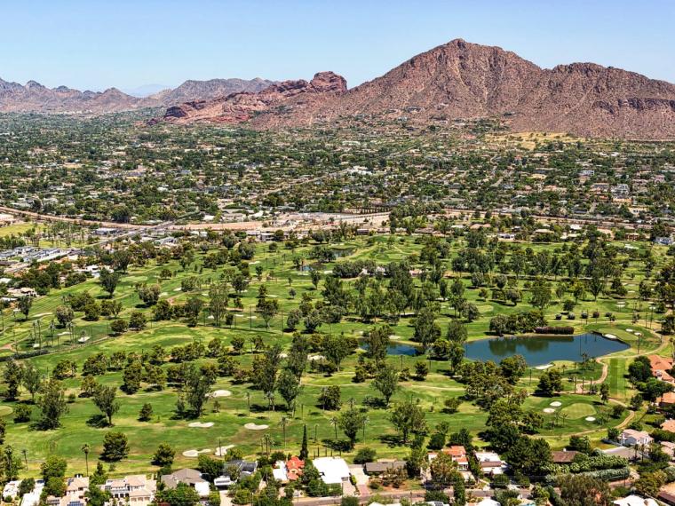 Aerial view of a golf course and homes below Camelback Mountain in Phoenix, Arizona