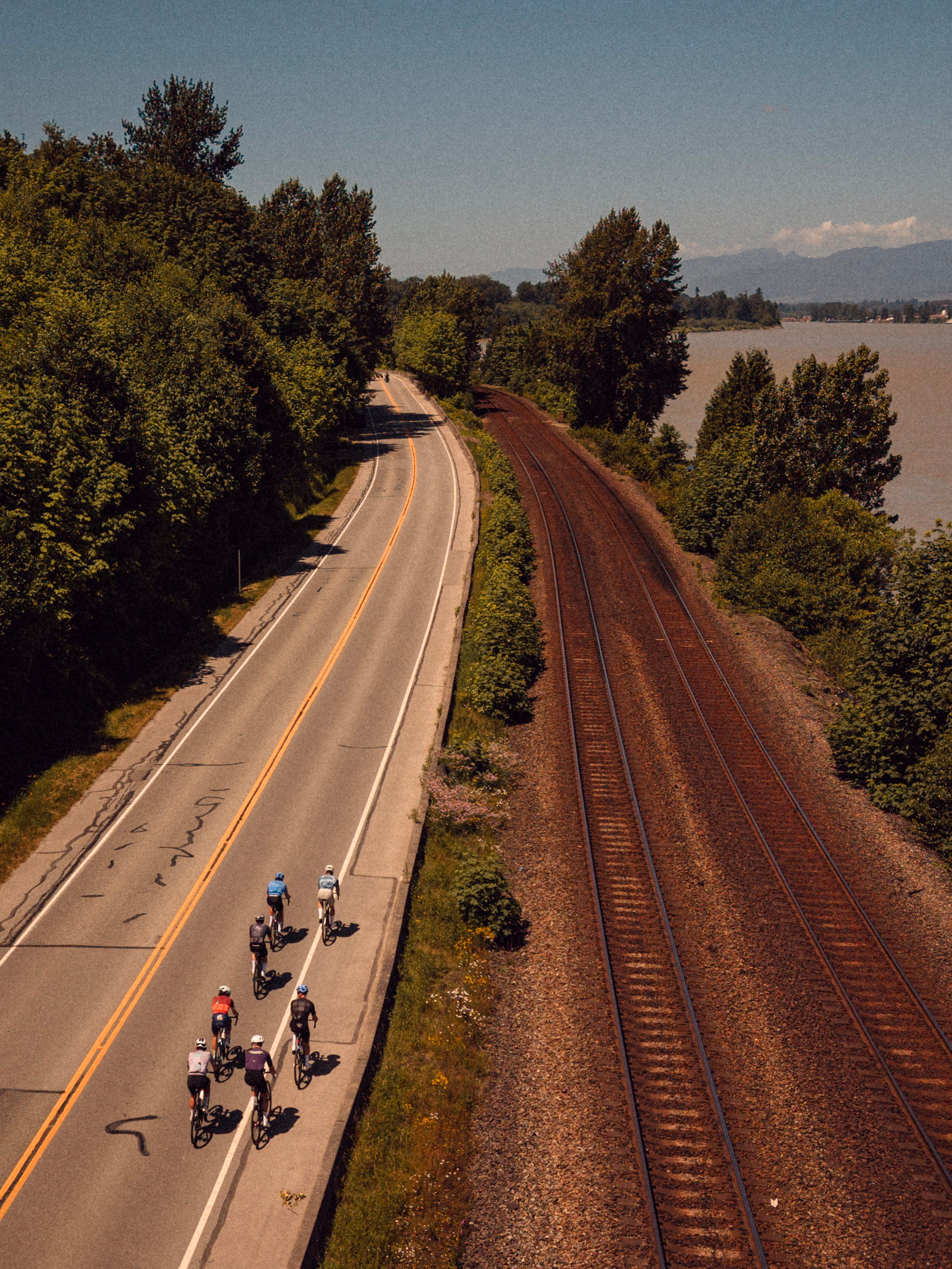 photo of cyclists beside traintracks taken from the air 