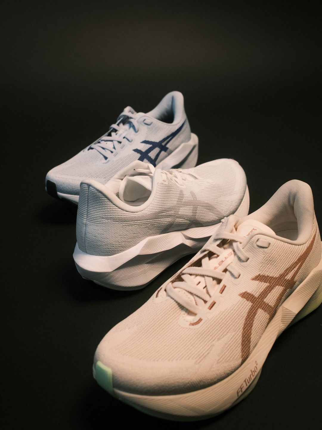 A pair of ASICS Novablast 6 running shoes in two colourways on a dark studio background