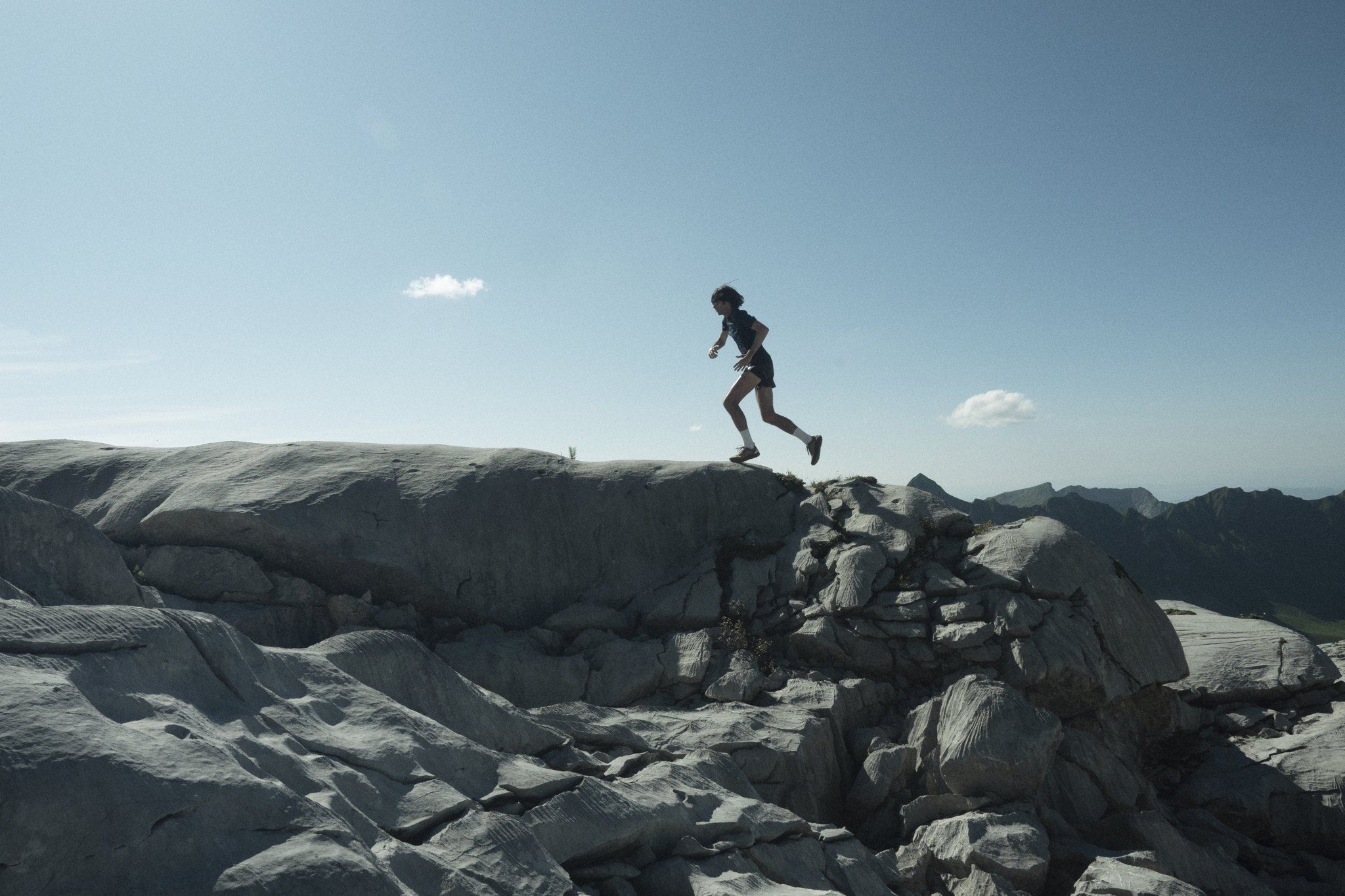 Trail runner leaping across rocky terrain