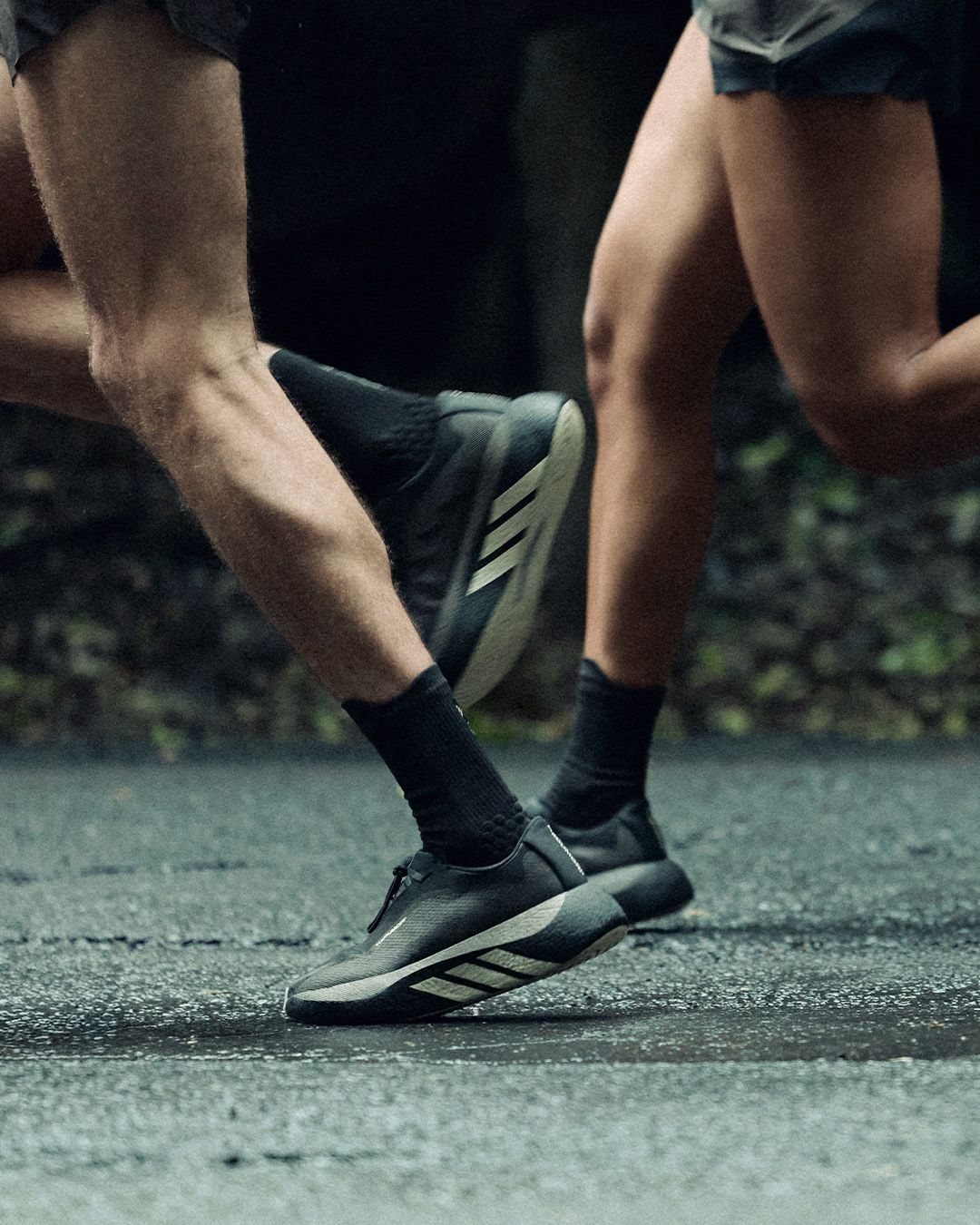 adidas x Hermanos Koumori Hyperboost Edge on two runners, wet forest road