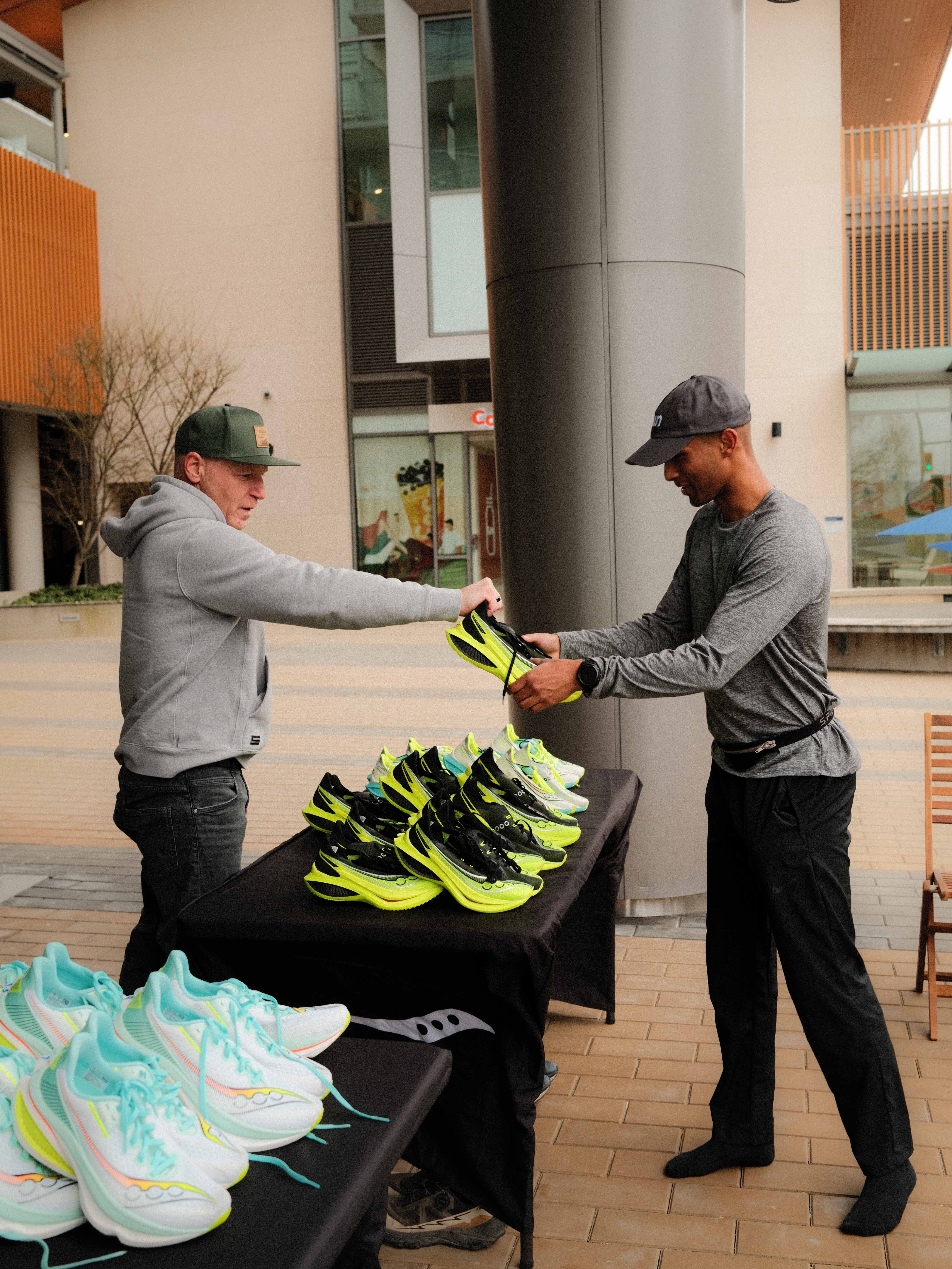Man handing a pair of Saucony running shoes to a .RUN Club member