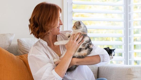 Lady holds and looks into the eyes of her pet after reading about gingivitis in cats Lady holds and looks into the eyes of her pet after reading about gingivitis in cats