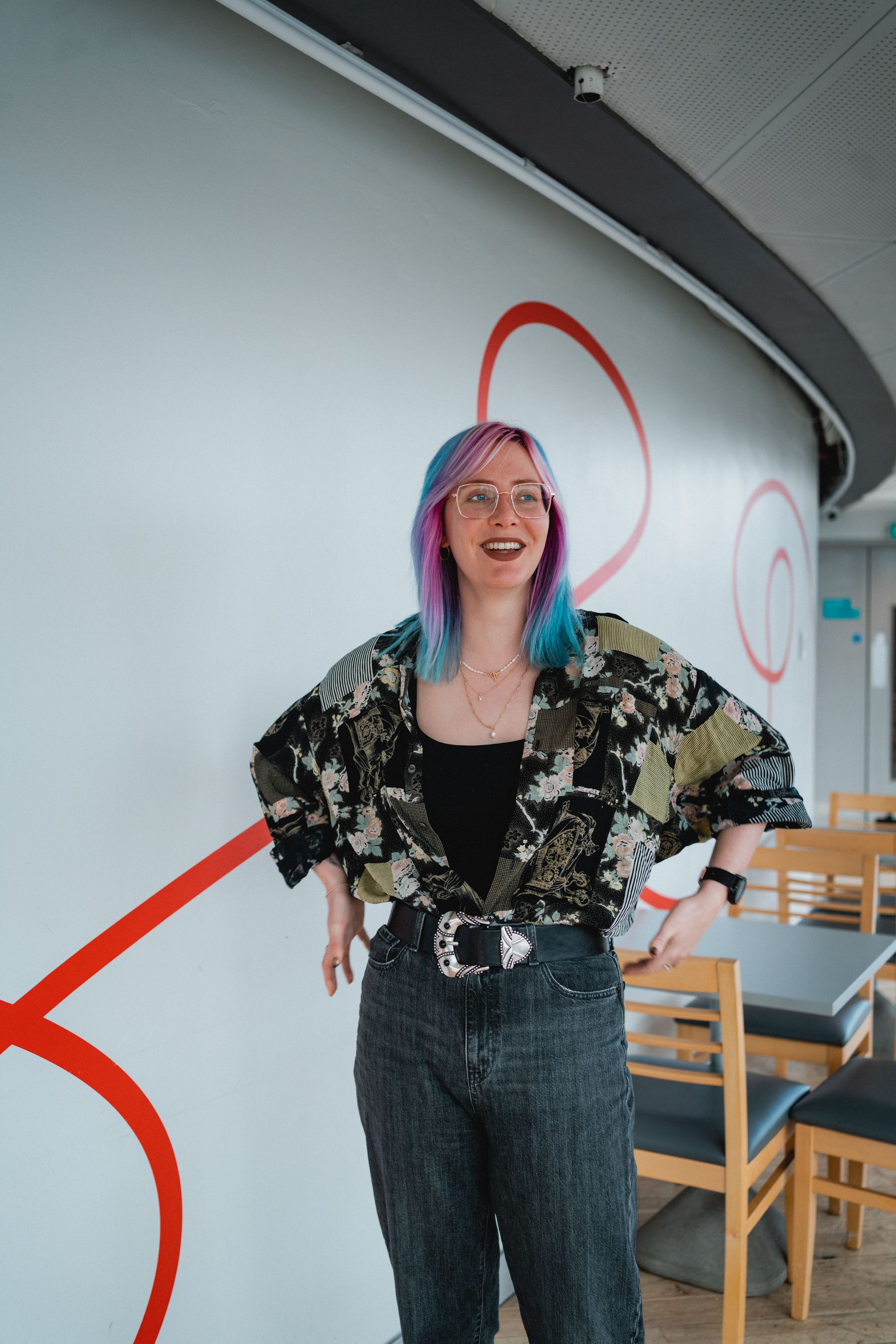 A colourful haired woman standing laughing on the first floor of ARC Stockton Arts Centre