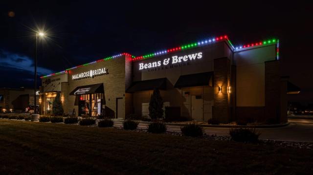 A row of shopfronts lit in red and green for Christmas