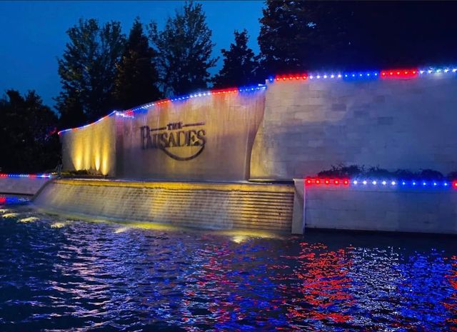 A community entrance monument and water feature lit in red, white and blue