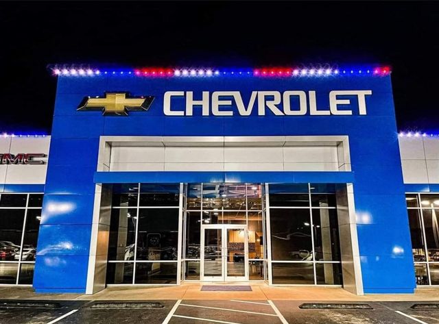 A car dealership showroom lit in red, white and blue