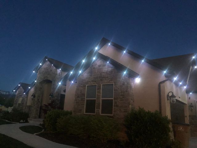 Cool white down lighting across a stone home