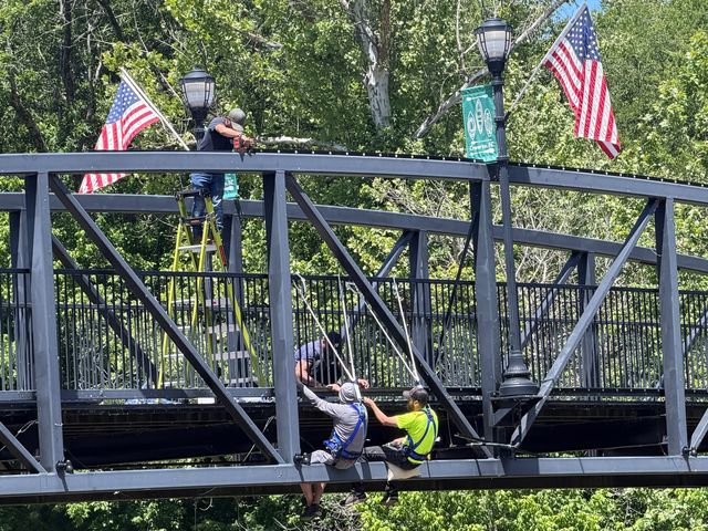 Installers fitting permanent lighting to a pedestrian bridge