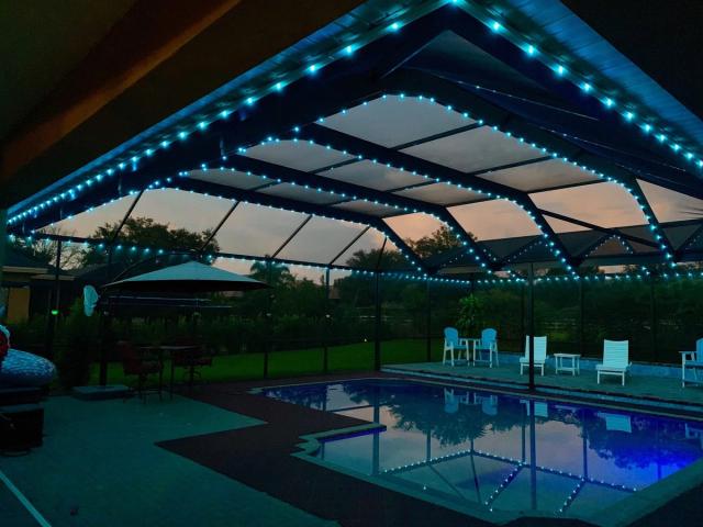 Teal lighting along a screened pool enclosure