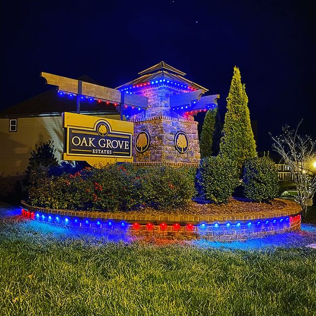 A stone entrance monument with lighting along the surrounding beds