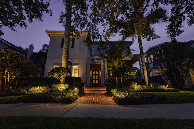 Uplighting on palms in front of a Mediterranean-style home