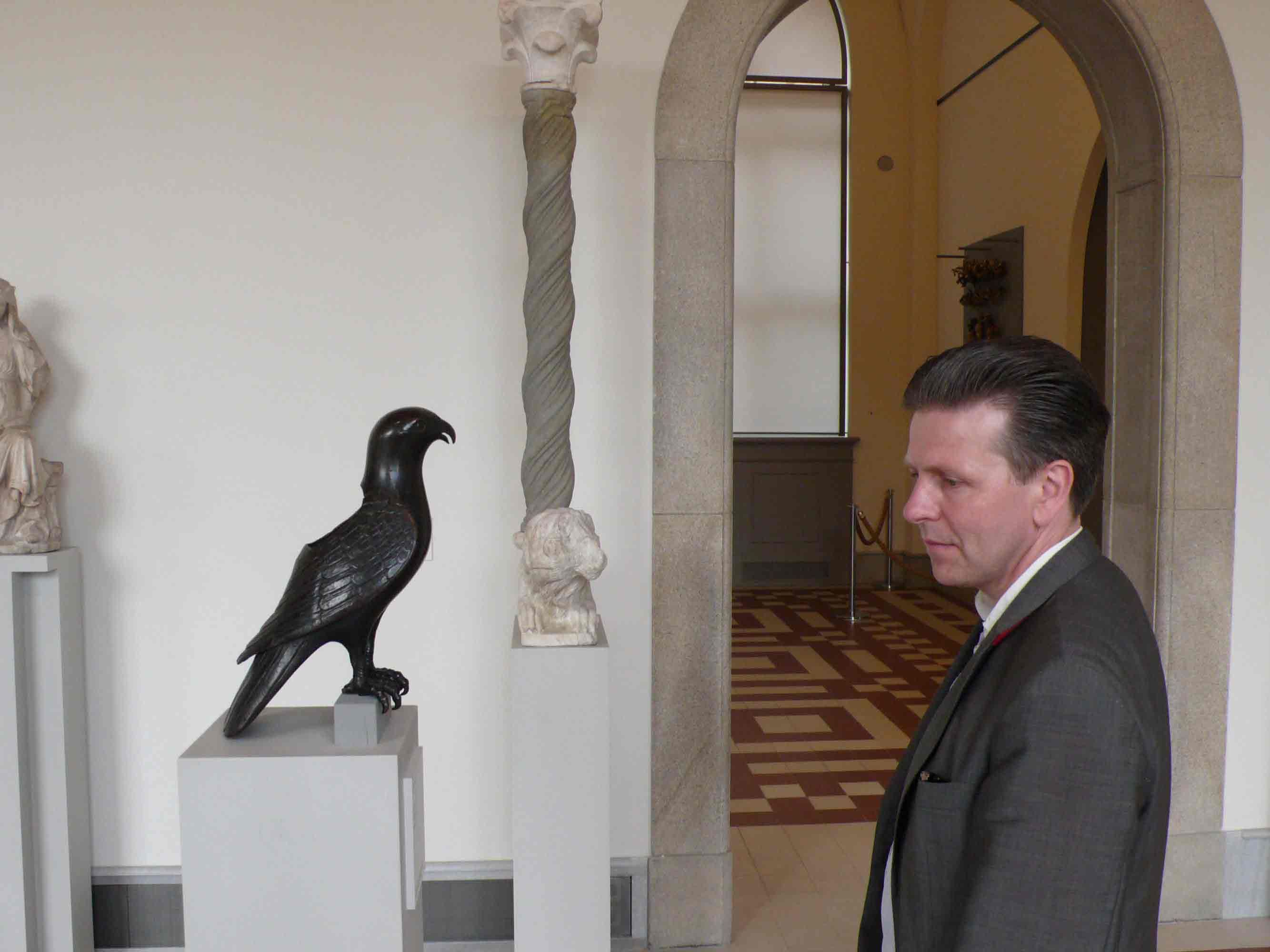 photograph of the Artist Mark Alexander in the Bode Museum looking at a bronze bird,  