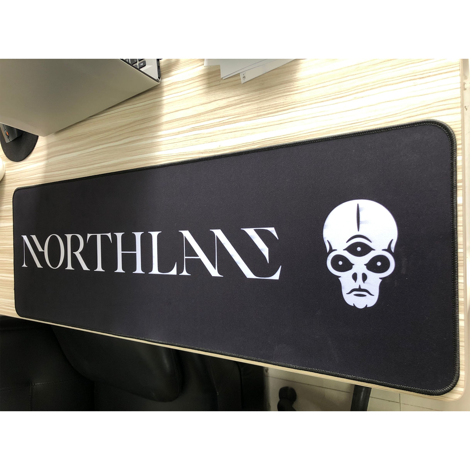 Angled image of the desk pad highlighting the stitched edging and smooth surface material.