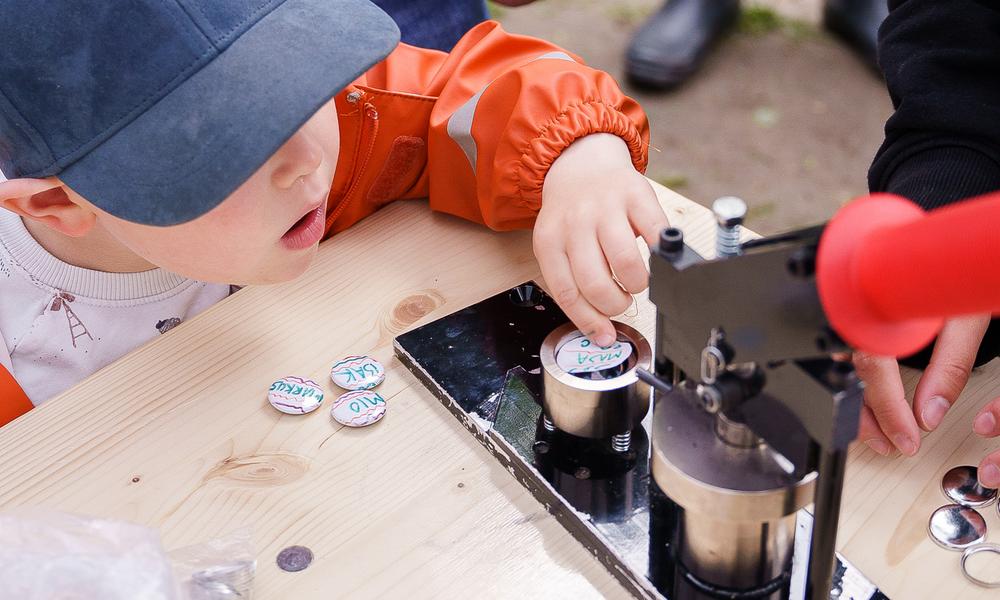 Bilda av et barn som legger en button i buttonsmaskinen.