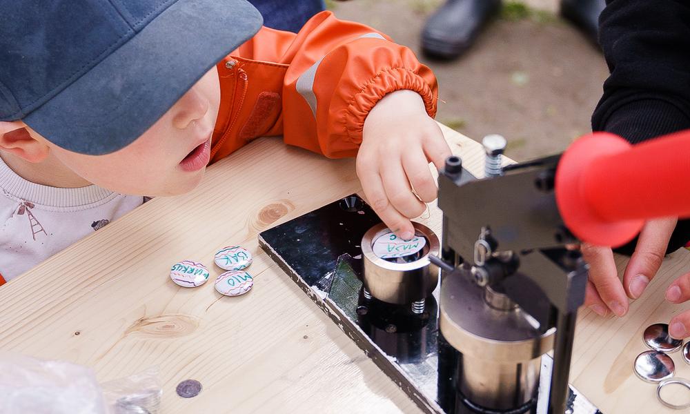 Bilde av et barn som legger en button i buttonsmaskinen.