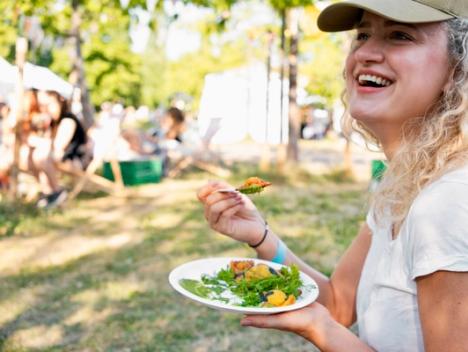 Kvinne som smiler og koser seg med mat på festivalen