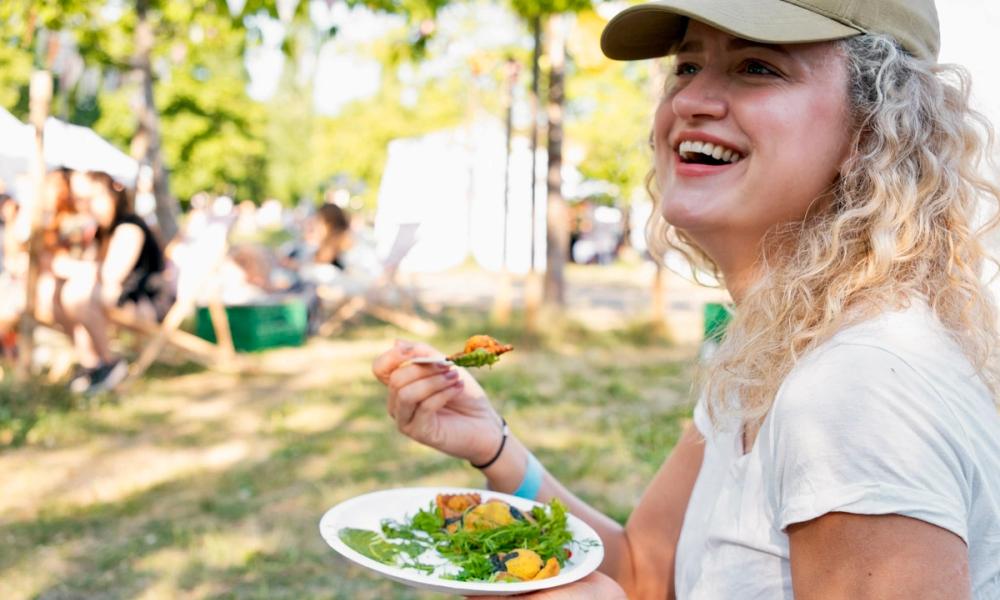 Kvinne som smiler og koser seg med mat på festivalen
