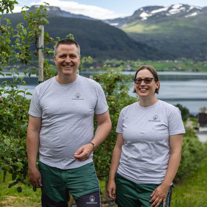 Bilde av to bønder på en vakker fruktgård med en fjord i bakgrunnen 