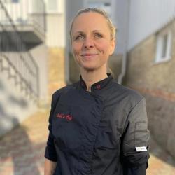 Julie Colin står i kokkejakke utendørs og ser i kamera.