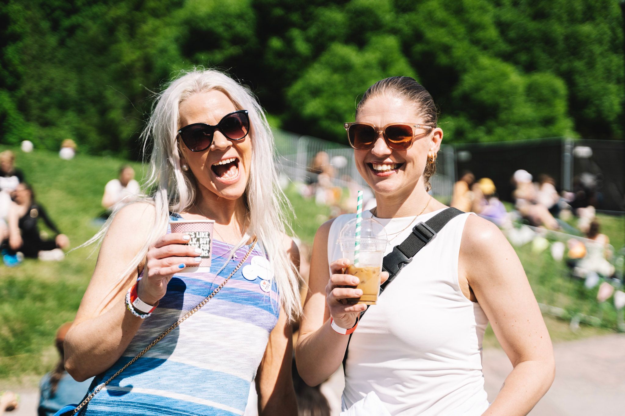 To kvinner som smiler med forfriskende drikke i hånden