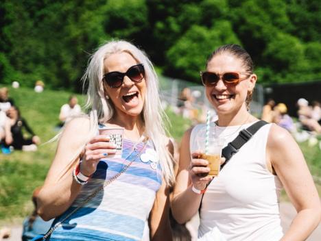 To kvinner som smiler med forfriskende drikke i hånden