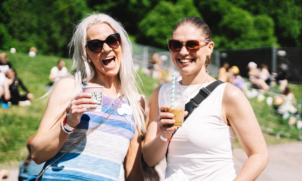 To kvinner som smiler med forfriskende drikke i hånden