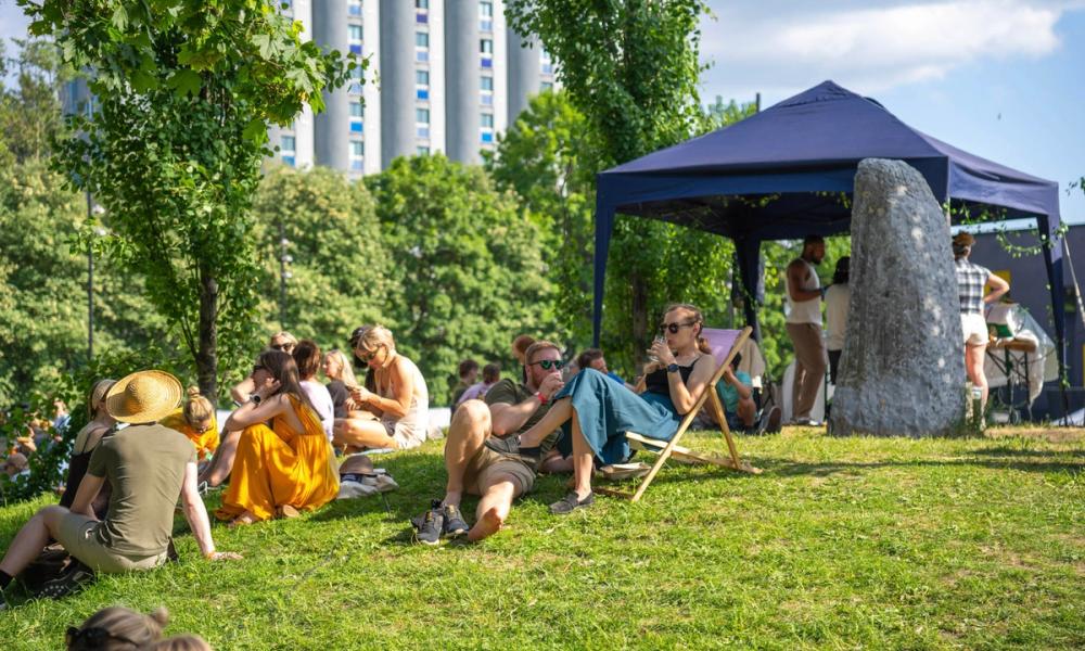 Folk som slapper av på gresset i sola