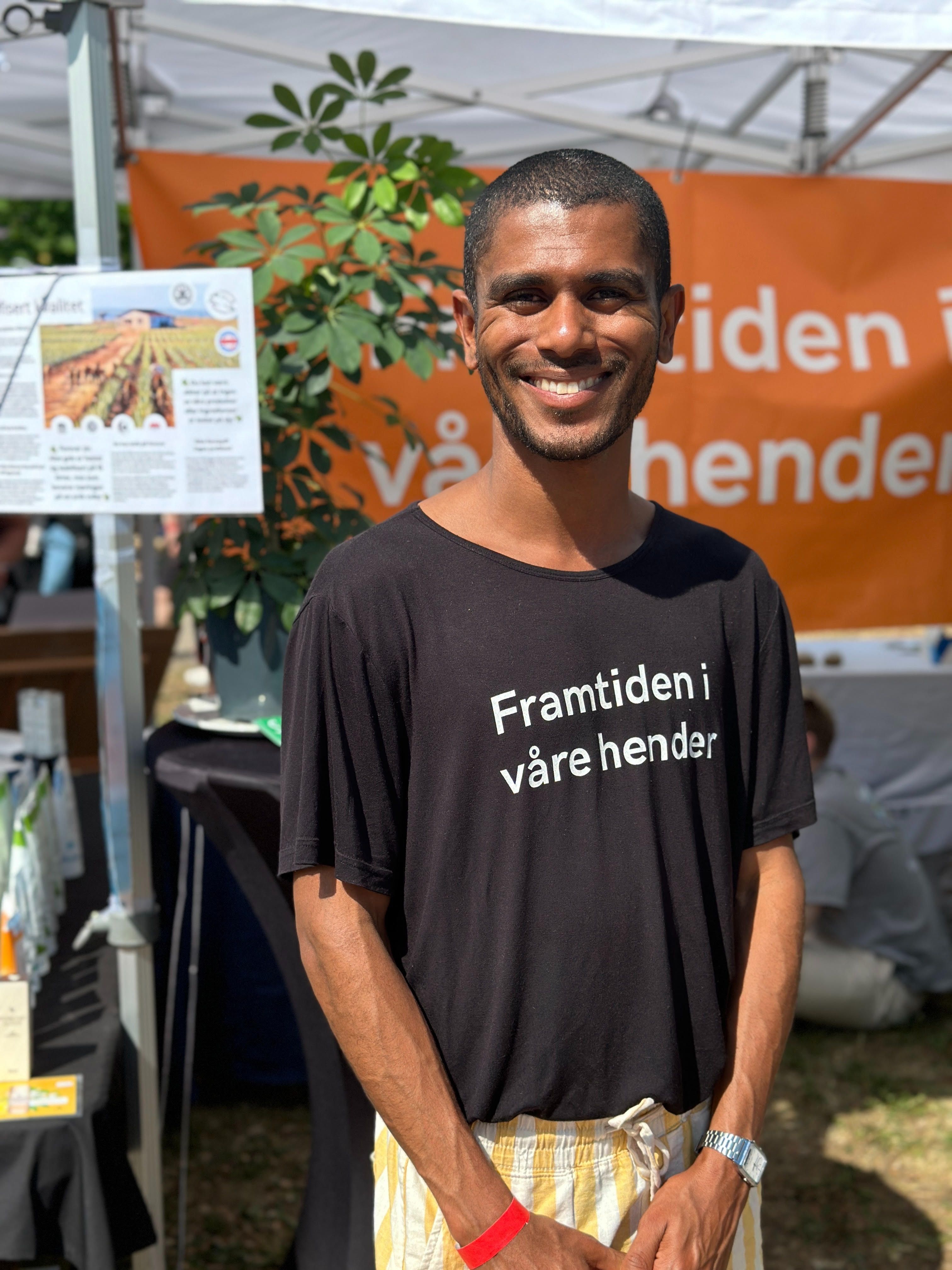 En person smiler foran standen 