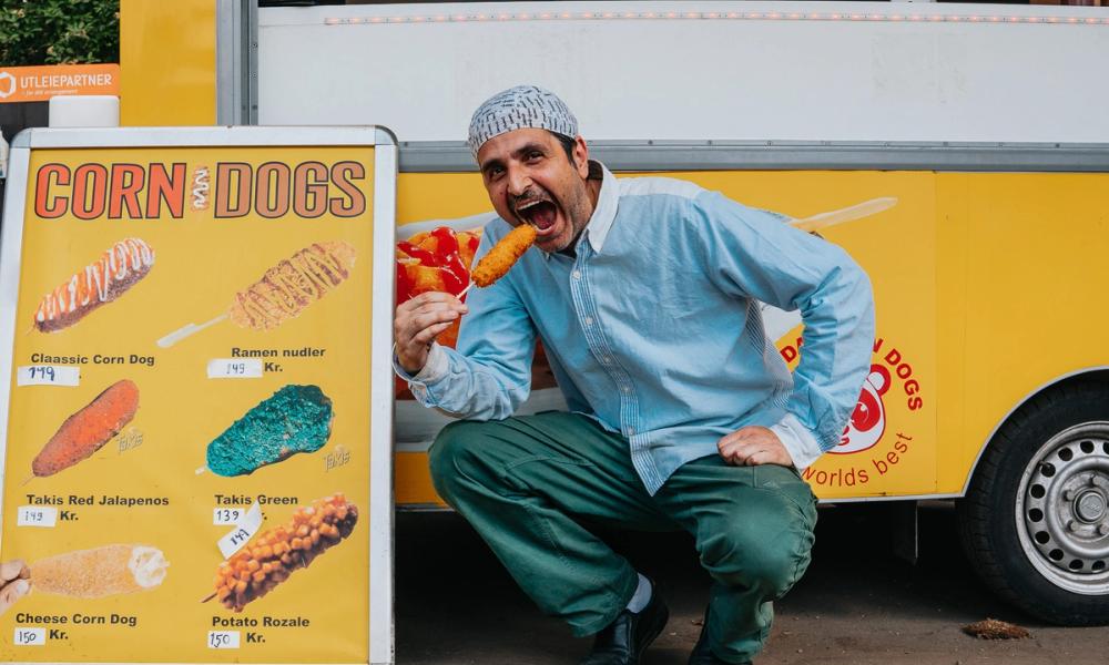 Bilde av mann som spiser corn dogs.