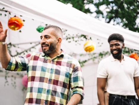 To smilende menn på festivalen, med et telt i bakgrunnen