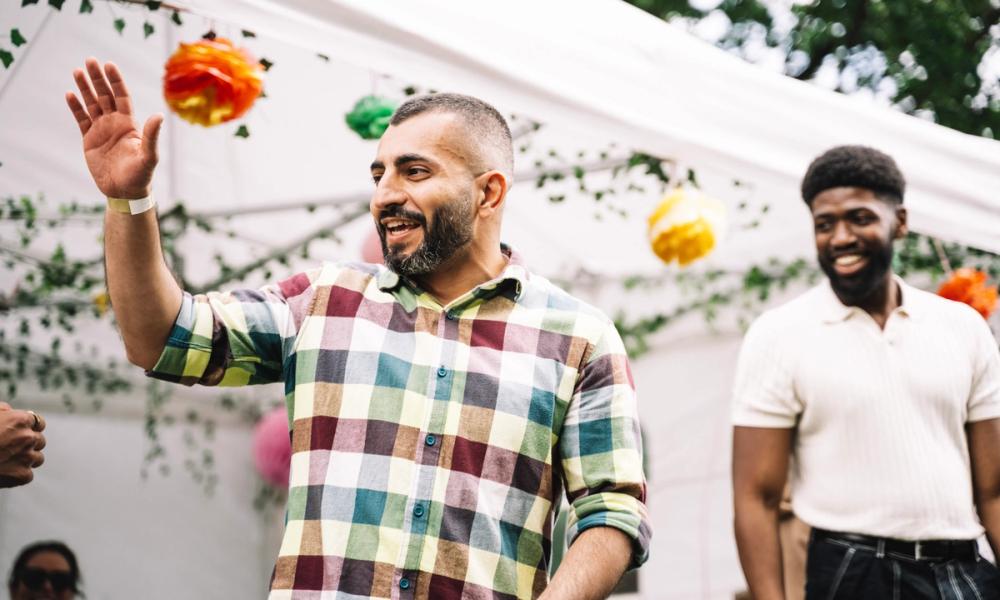To smilende menn på festivalen, med et telt i bakgrunnen