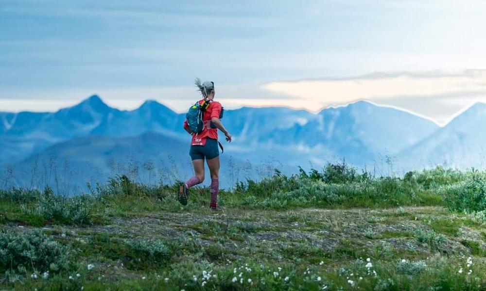 Bilde av Mari Nustad Mauland som løper på fjellet med fjell i bakgrunnen.