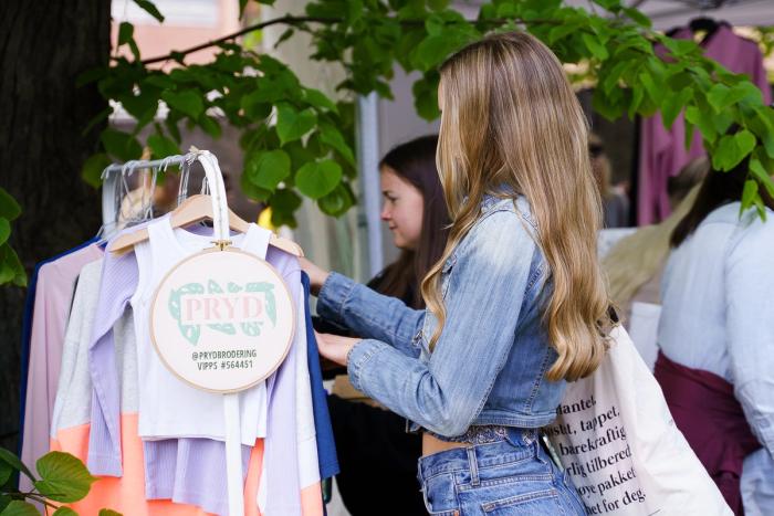 Dame ser på klær på utstilling på en stand.