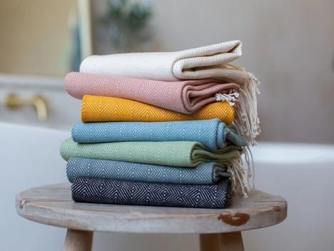 Bilde av håndvevde tekstiler i forskjellige farger på en krakk. 