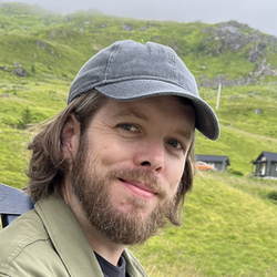 Smilende mann med caps, grønn jakke og