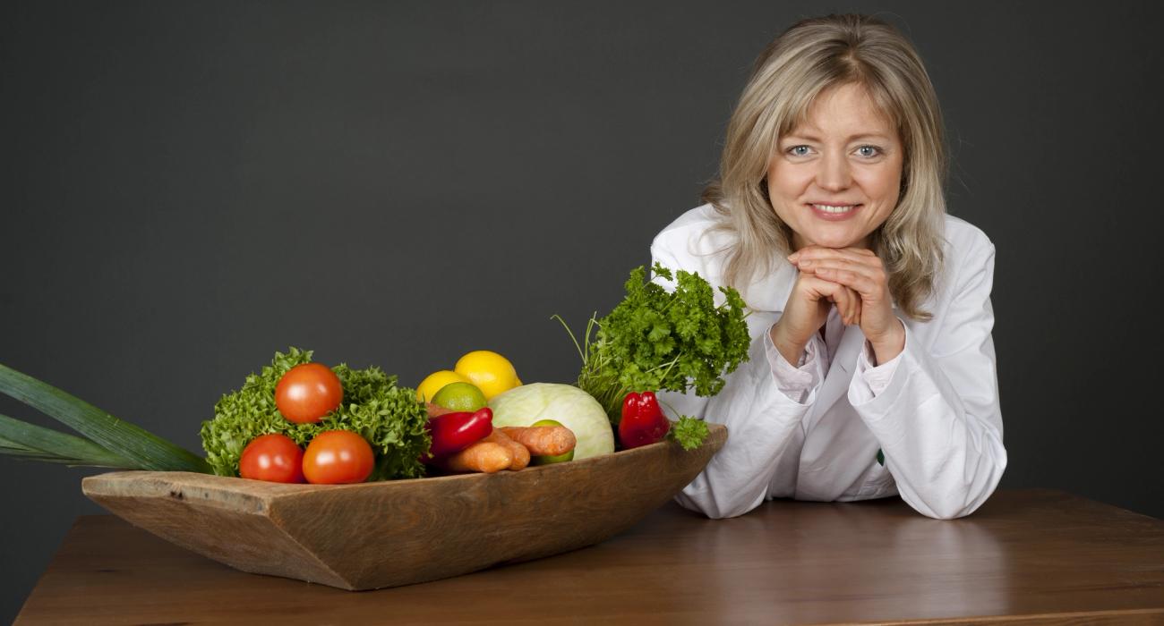Bilde av Tanja bak et bord med grønnsaker.
