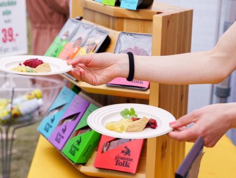 Bilde av hender som deler ut gratis smaksprøver på Grønne Folks produkter. 