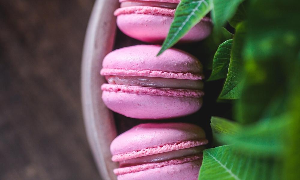 Bilde av en skål med rosa makroner, grønne mintblad i forgrunden