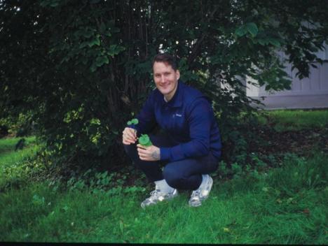 Mann sitter på huk under et tre