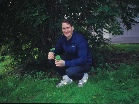 Mann sitter på huk under et tre