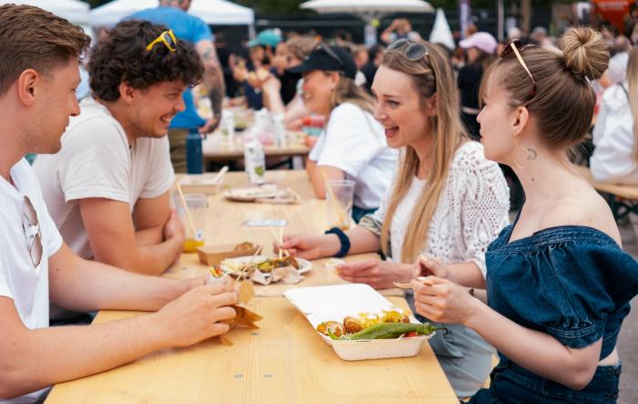 Festivaldeltagere ler og spiser mat på festivalen