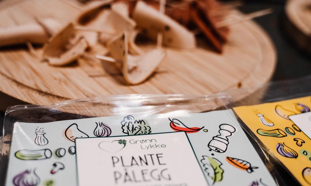 Bilde av en pakke med plantepålegg foran smaksprøver av vegansk påleggspølse.