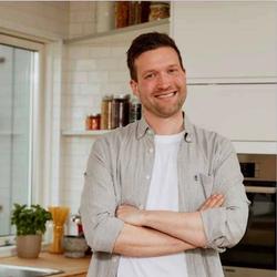 Kristoffer Tvilde står på kjøkkenet og smiler inn i kamera