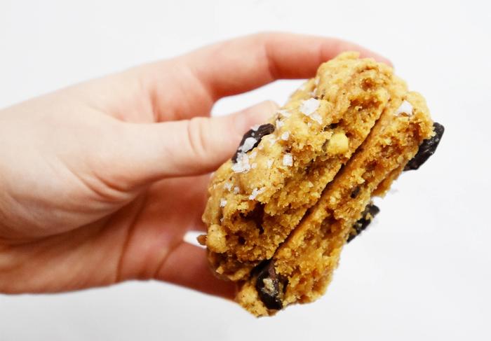 BIlde av en hånd som holder en cookie delt i to. 