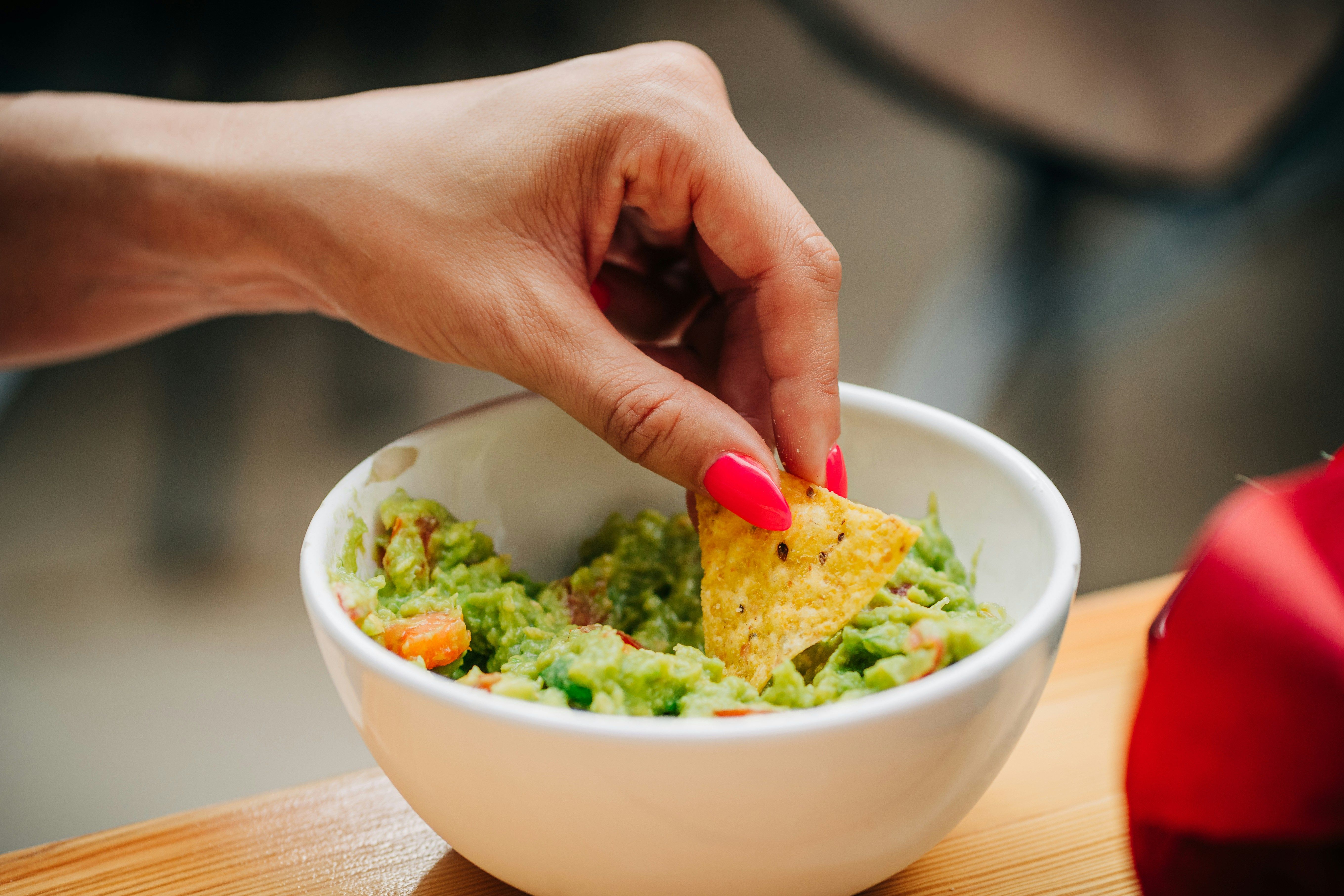 Hånd som tar guacamole på nacho