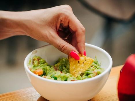 Hånd som tar guacamole på nacho