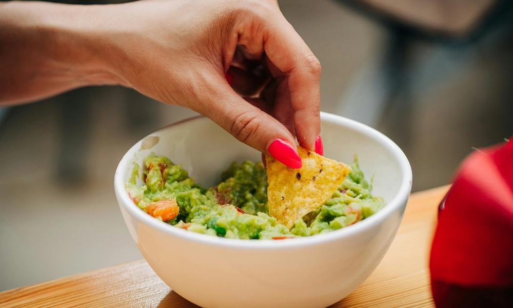 Hånd som tar guacamole på nacho