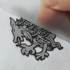 Peeling clear carrier sheet from a custom 3D high density silicone reflective heat transfer dragon logo on fabric